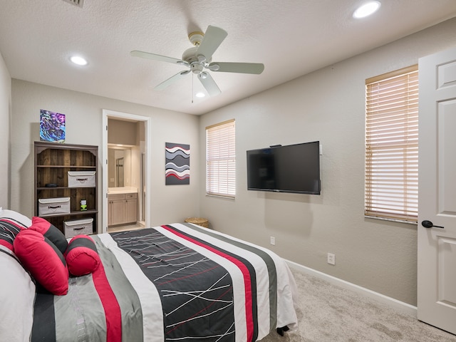 bedroom featuring carpet, multiple windows, ceiling fan, and ensuite bath