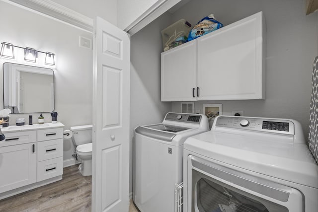 washroom with cabinets, light hardwood / wood-style flooring, and washer and clothes dryer