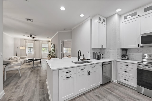 kitchen with kitchen peninsula, appliances with stainless steel finishes, ceiling fan, sink, and white cabinets