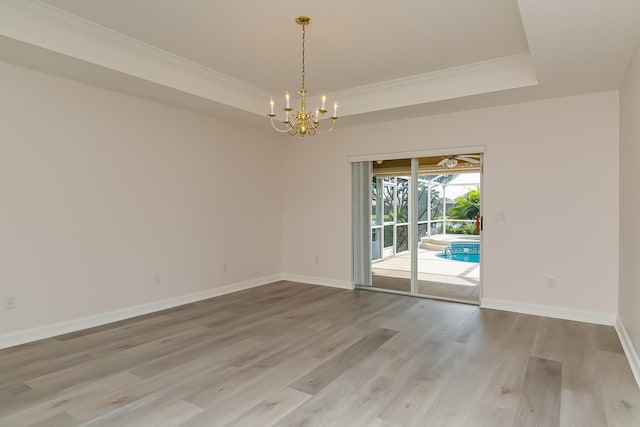 unfurnished room featuring crown molding, hardwood / wood-style flooring, and a raised ceiling