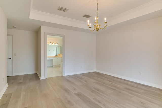 unfurnished room with a raised ceiling, ornamental molding, a chandelier, and light hardwood / wood-style flooring