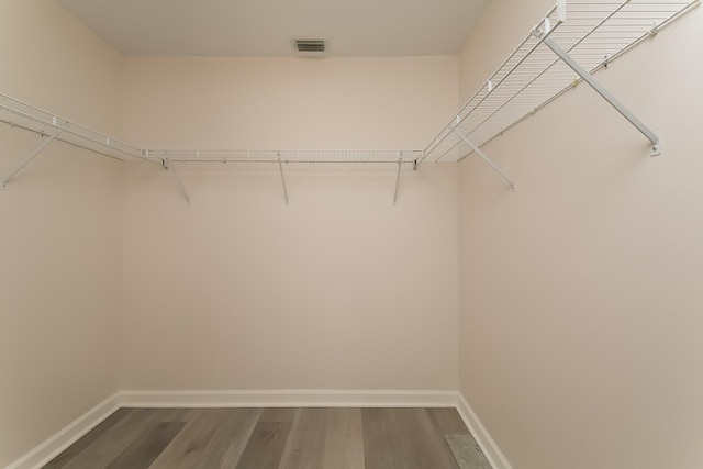 walk in closet with dark wood-type flooring