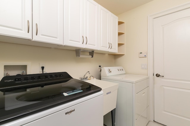 washroom with sink, washing machine and dryer, and cabinets