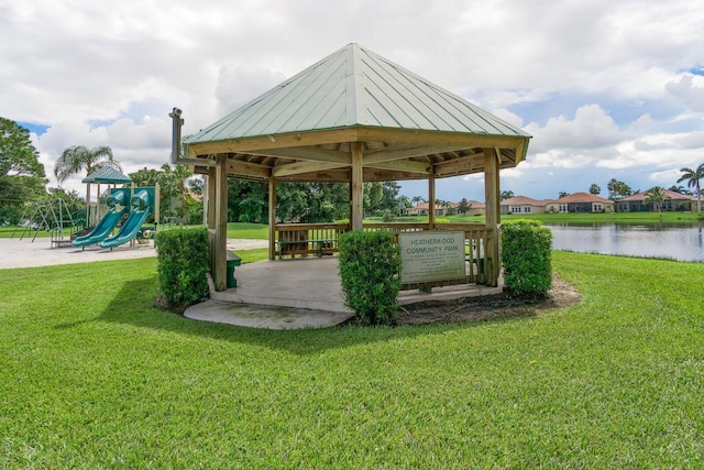 view of community with a playground, a water view, and a lawn