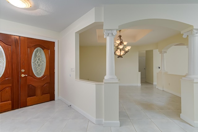 foyer featuring light tile patterned floors and decorative columns