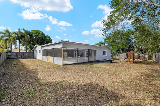 rear view of property with a sunroom, a playground, a yard, and a patio