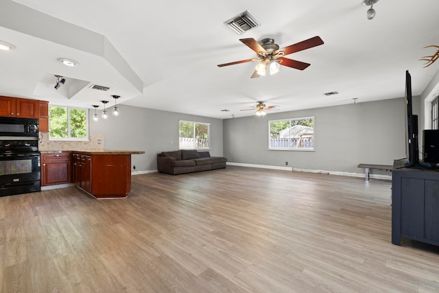 interior space featuring ceiling fan, kitchen peninsula, light hardwood / wood-style floors, decorative backsplash, and black appliances