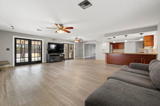 living room with ceiling fan, french doors, and light wood-type flooring