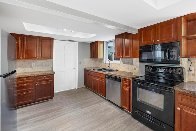 kitchen with light stone countertops, tasteful backsplash, sink, black appliances, and light hardwood / wood-style floors