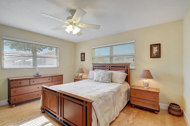 bedroom featuring ceiling fan, light hardwood / wood-style flooring, and multiple windows