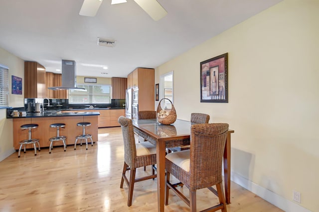 dining area with light hardwood / wood-style flooring and ceiling fan