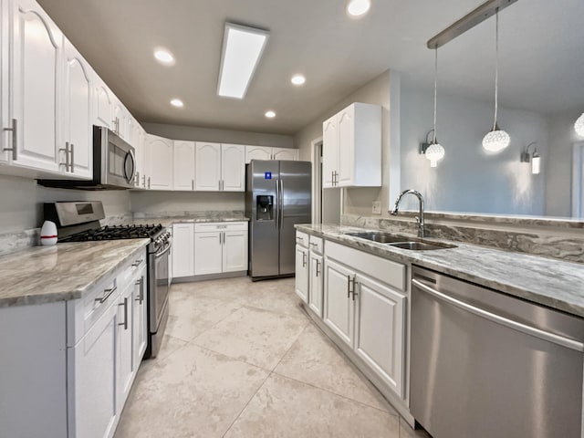 kitchen featuring white cabinets, appliances with stainless steel finishes, pendant lighting, and sink