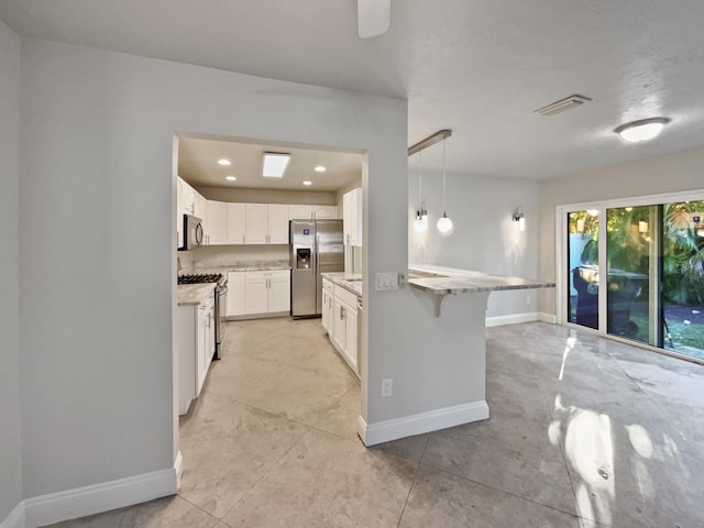 kitchen with light stone countertops, appliances with stainless steel finishes, pendant lighting, white cabinetry, and a breakfast bar area