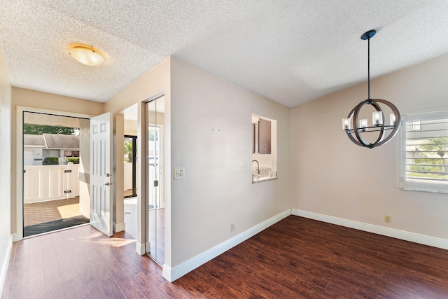 interior space with a textured ceiling, plenty of natural light, dark wood-type flooring, and an inviting chandelier