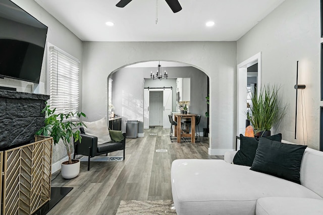 living room with a barn door, light hardwood / wood-style floors, and ceiling fan