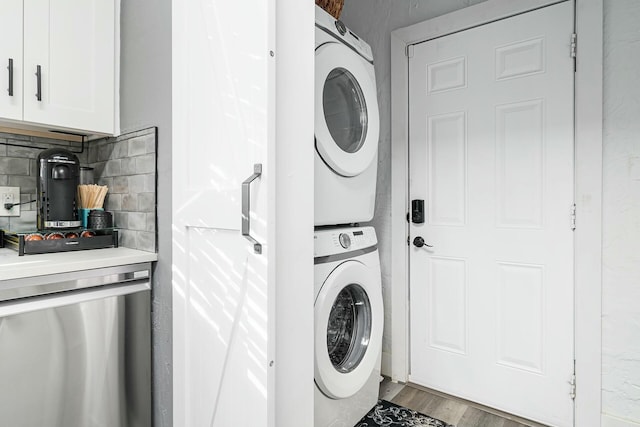 laundry room featuring stacked washer / dryer and light hardwood / wood-style flooring