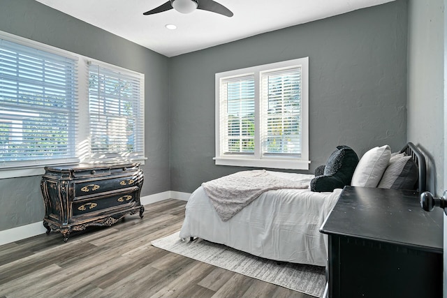 bedroom featuring hardwood / wood-style flooring, ceiling fan, and multiple windows