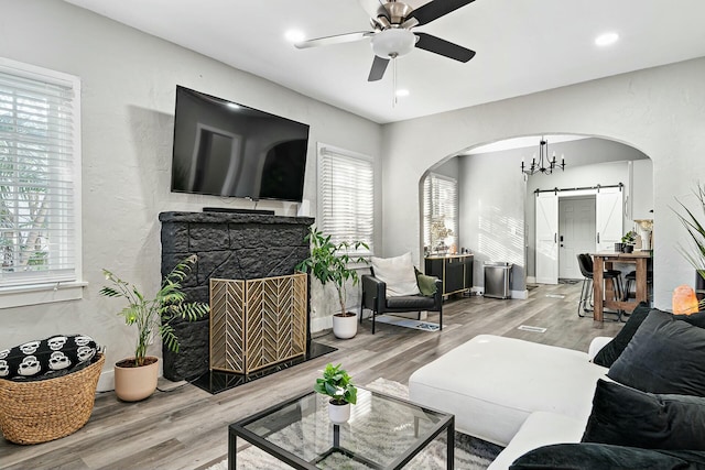 living room with a barn door, hardwood / wood-style flooring, and ceiling fan