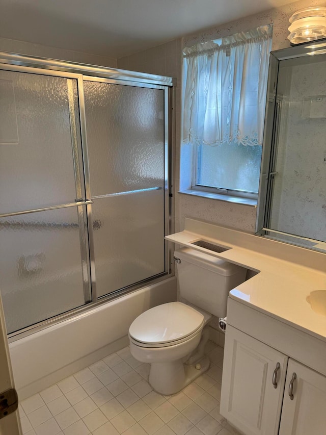 full bathroom featuring shower / bath combination with glass door, vanity, tile patterned floors, and toilet