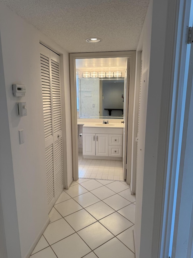 7516 N Devon Dr Unit 212, Tamarac, FL 33321 - hallway featuring a textured ceiling, a sink, light tile patterned floors, baseboards, and recessed lighting