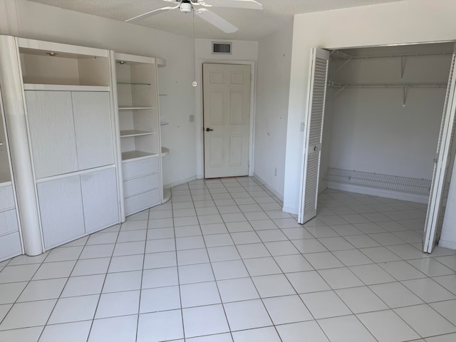 unfurnished bedroom with ceiling fan, light tile patterned flooring, and a textured ceiling