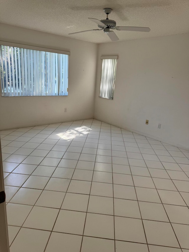 tiled empty room featuring ceiling fan and a textured ceiling