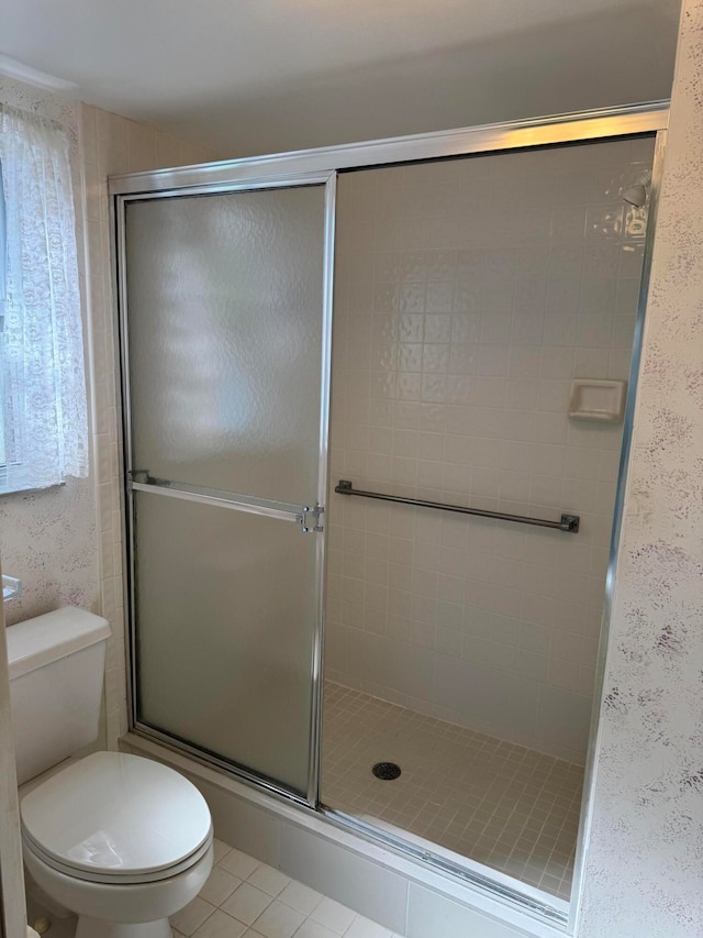 bathroom with tile patterned floors, a shower with door, and toilet