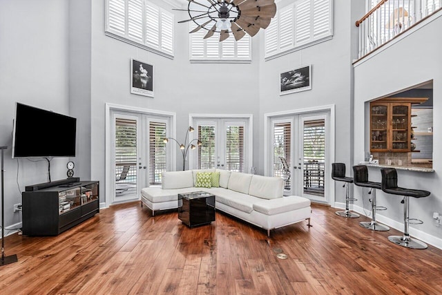 living room with french doors, hardwood / wood-style flooring, ceiling fan, and a high ceiling