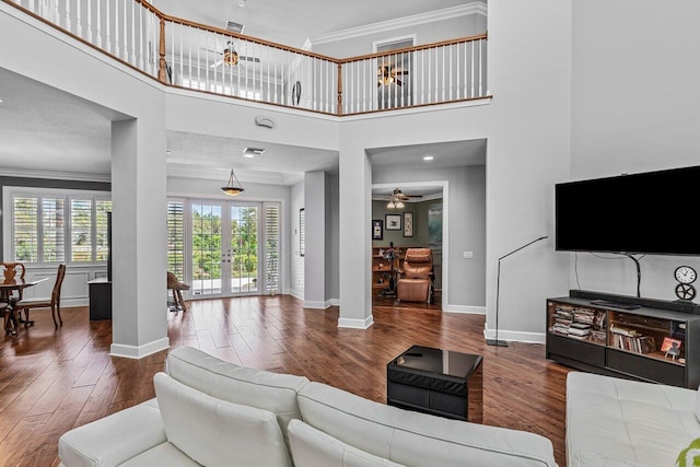 living room featuring ceiling fan, french doors, a high ceiling, crown molding, and hardwood / wood-style flooring