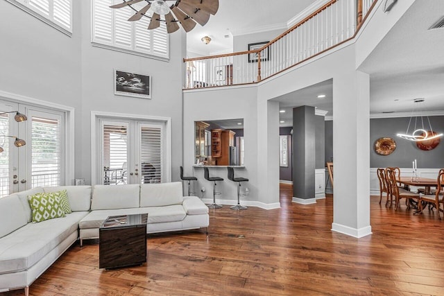 living room with french doors, a towering ceiling, ceiling fan, and ornamental molding