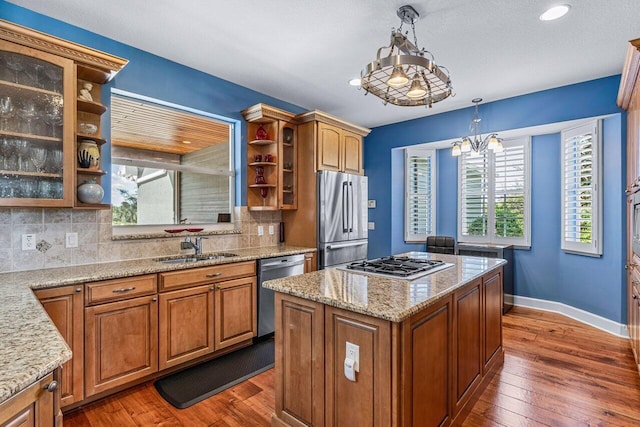 kitchen featuring sink, a center island, an inviting chandelier, decorative backsplash, and appliances with stainless steel finishes