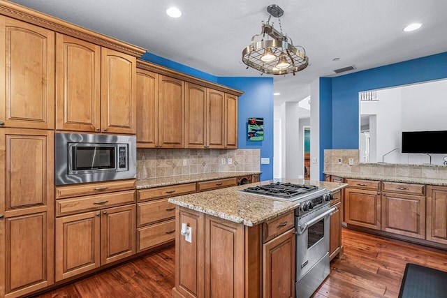 kitchen featuring backsplash, light stone counters, stainless steel appliances, dark hardwood / wood-style floors, and hanging light fixtures