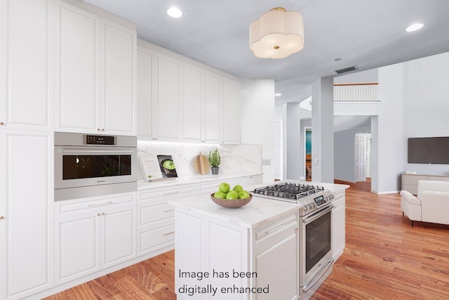 kitchen featuring lofted ceiling, light hardwood / wood-style flooring, a kitchen island, white cabinetry, and stainless steel appliances