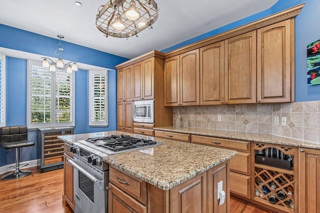 kitchen featuring light stone countertops, decorative backsplash, hanging light fixtures, and appliances with stainless steel finishes