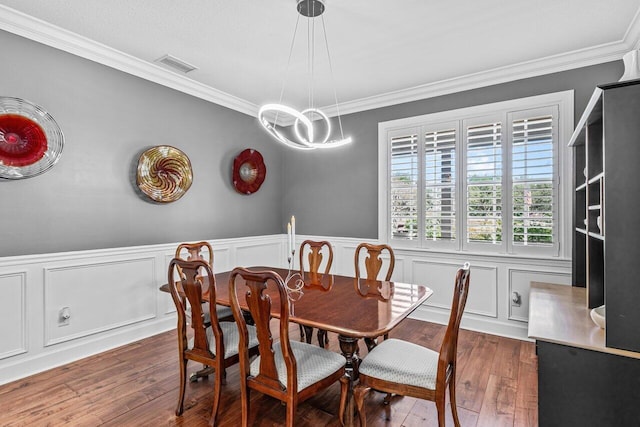 dining space featuring dark hardwood / wood-style flooring, ornamental molding, and a chandelier