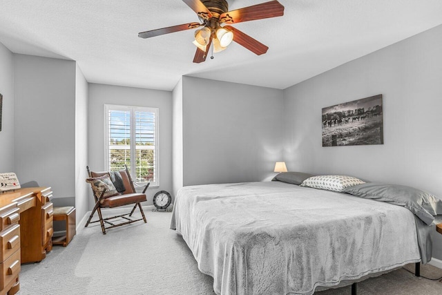 carpeted bedroom featuring ceiling fan and a textured ceiling