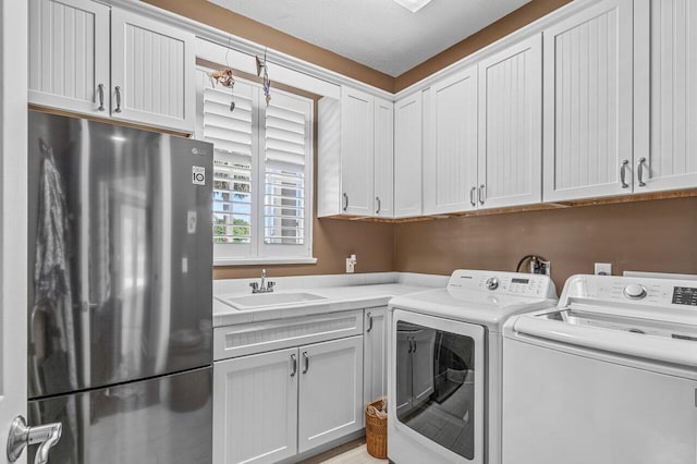 washroom with a textured ceiling, washing machine and dryer, and sink