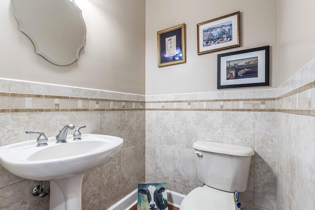 bathroom featuring tile walls and toilet