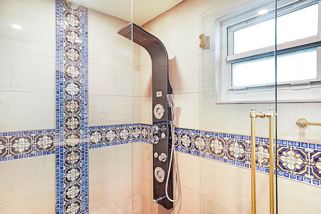 bathroom with a tile shower and tile walls