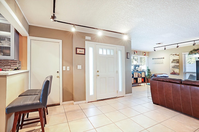 foyer entrance featuring a textured ceiling, rail lighting, and light tile patterned flooring