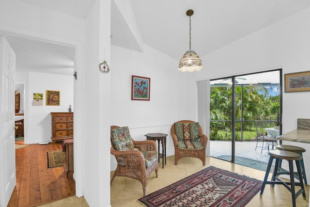 living area featuring a textured ceiling, light hardwood / wood-style flooring, and lofted ceiling