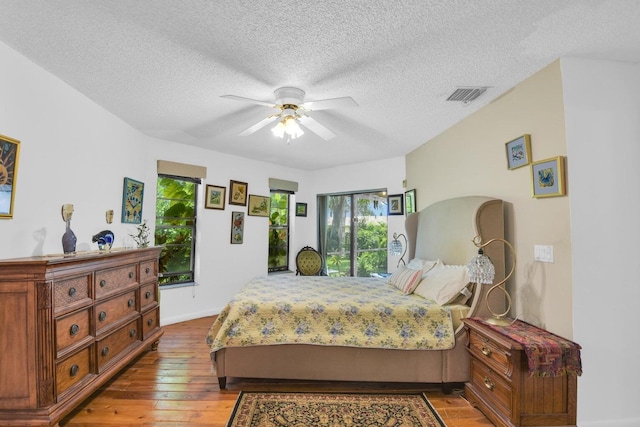 bedroom with hardwood / wood-style floors, a textured ceiling, and ceiling fan