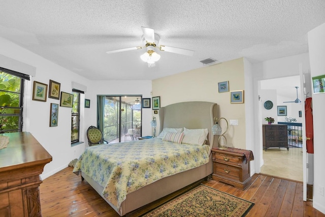 bedroom featuring access to outside, multiple windows, ceiling fan, and hardwood / wood-style flooring