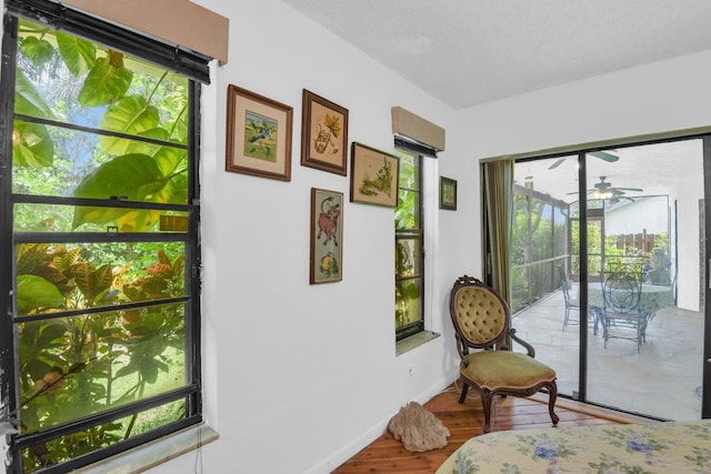 bedroom with access to exterior, wood-type flooring, and a textured ceiling