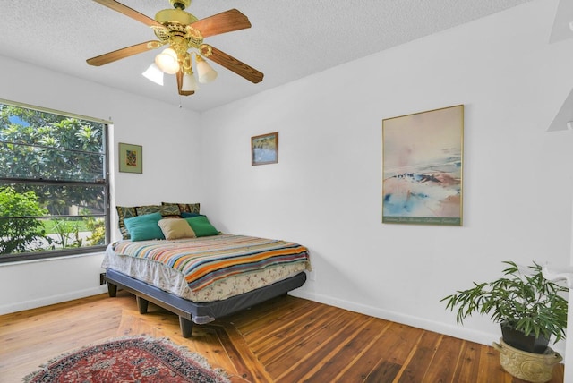 bedroom featuring ceiling fan, hardwood / wood-style floors, and a textured ceiling