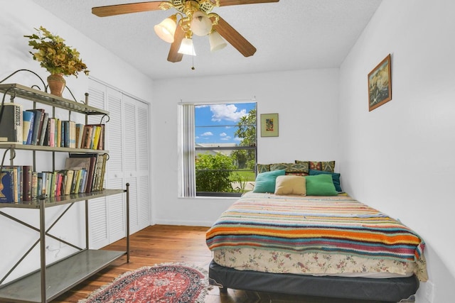 bedroom featuring ceiling fan, wood-type flooring, a textured ceiling, and a closet