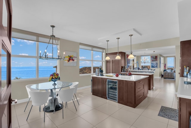 kitchen featuring an inviting chandelier, wine cooler, light tile patterned flooring, decorative light fixtures, and a water view