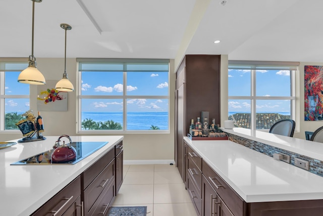 kitchen with black electric stovetop, light tile patterned floors, and pendant lighting