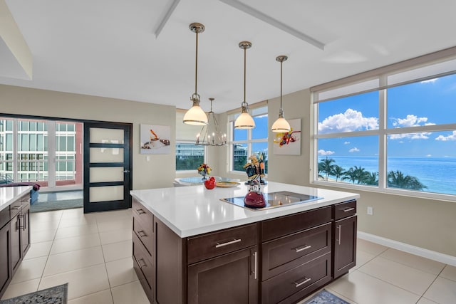 kitchen with hanging light fixtures, a chandelier, a water view, black electric stovetop, and light tile patterned flooring