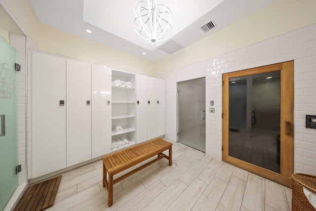 mudroom with light hardwood / wood-style floors, elevator, and a chandelier